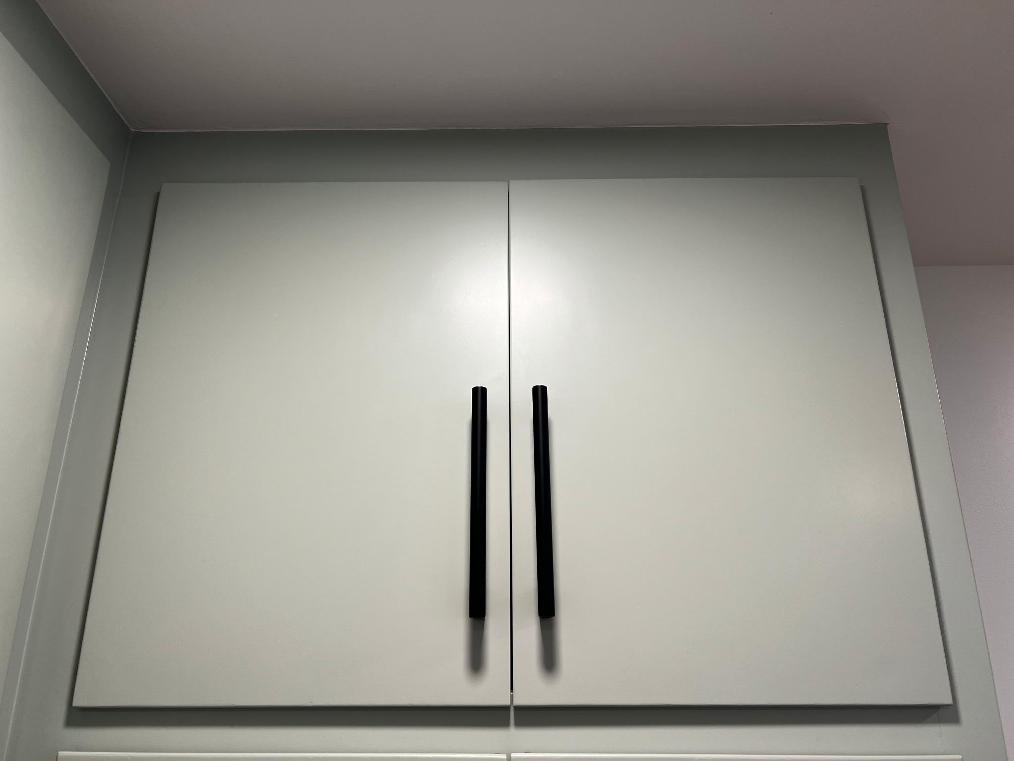 Cabinet doors painted a green shade with long black handles, in Omaha, NE.