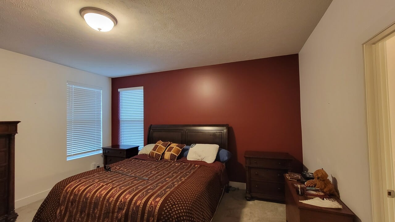 Bedroom with one accent wall that is painted a deep red. The other walls and ceilings are painted white.