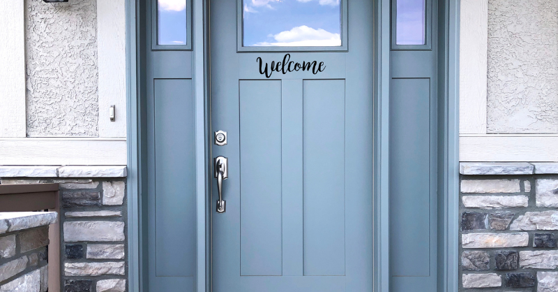 Muted baby blue painted exterior front door with windows and exterior dark brick in Omaha, NE.