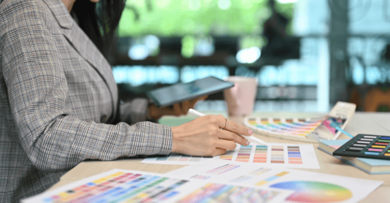 Woman sitting at a table with paint color spreads during a color consultation.