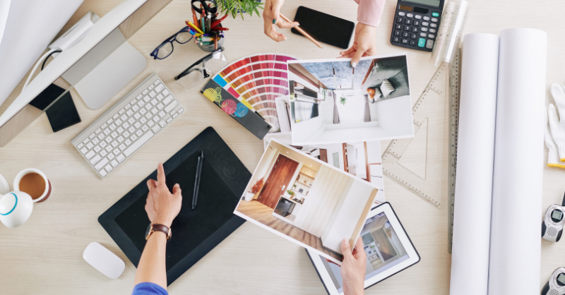 Overview of a table. 2 people sitting down looking at decor images and paint color samples and gradients.