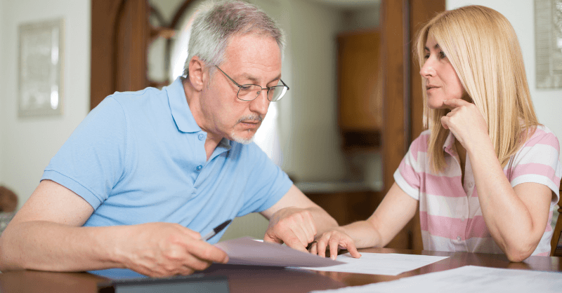 Man and woman talking together at a table and looking at papers.