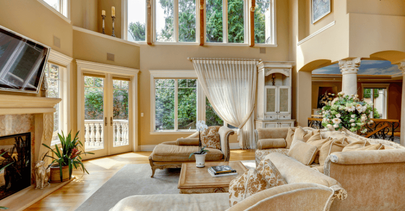 Yellow and beige monochromatic living room with large windows and couches.