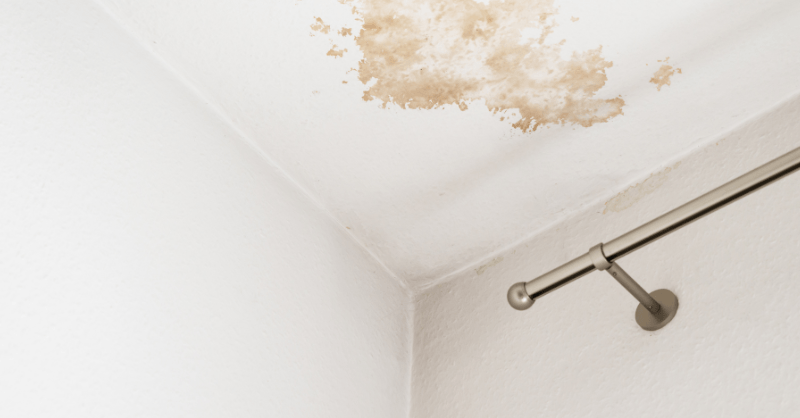 White ceiling with yellow water damage and white walls in a room.