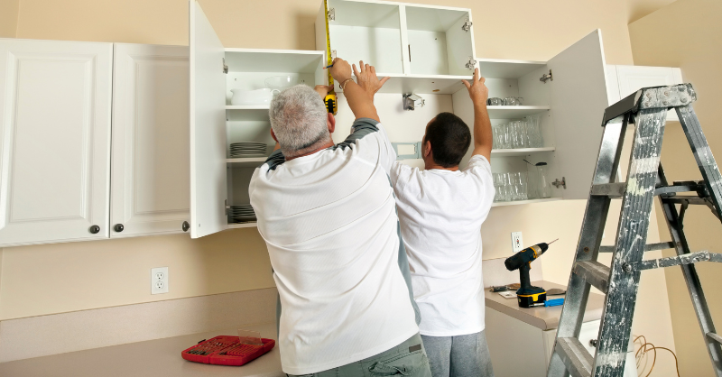 2 guys measure upper cabinet doors.
