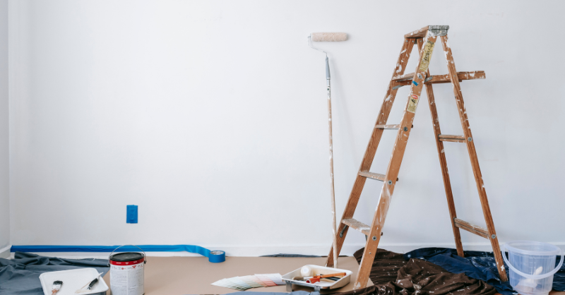 Room in the process of being painted white with supplies around the room.