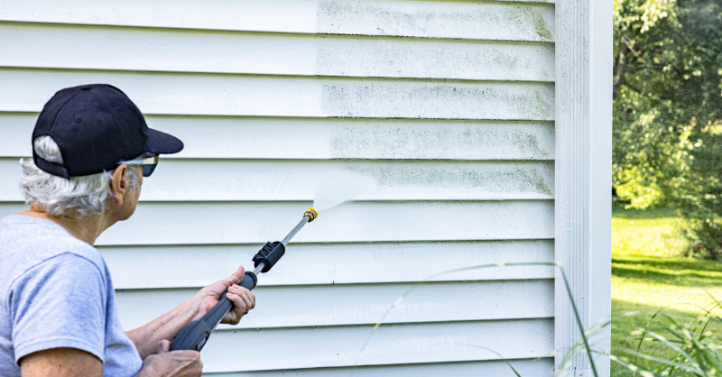 Lady power washing her home with a rented power washer in Omaha, NE.