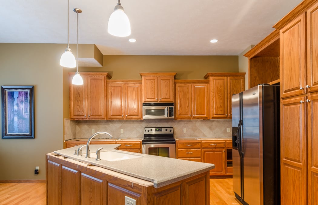 Kitchen with golden oak cabinets and white countertops before the cabinets were stained a dark brown.