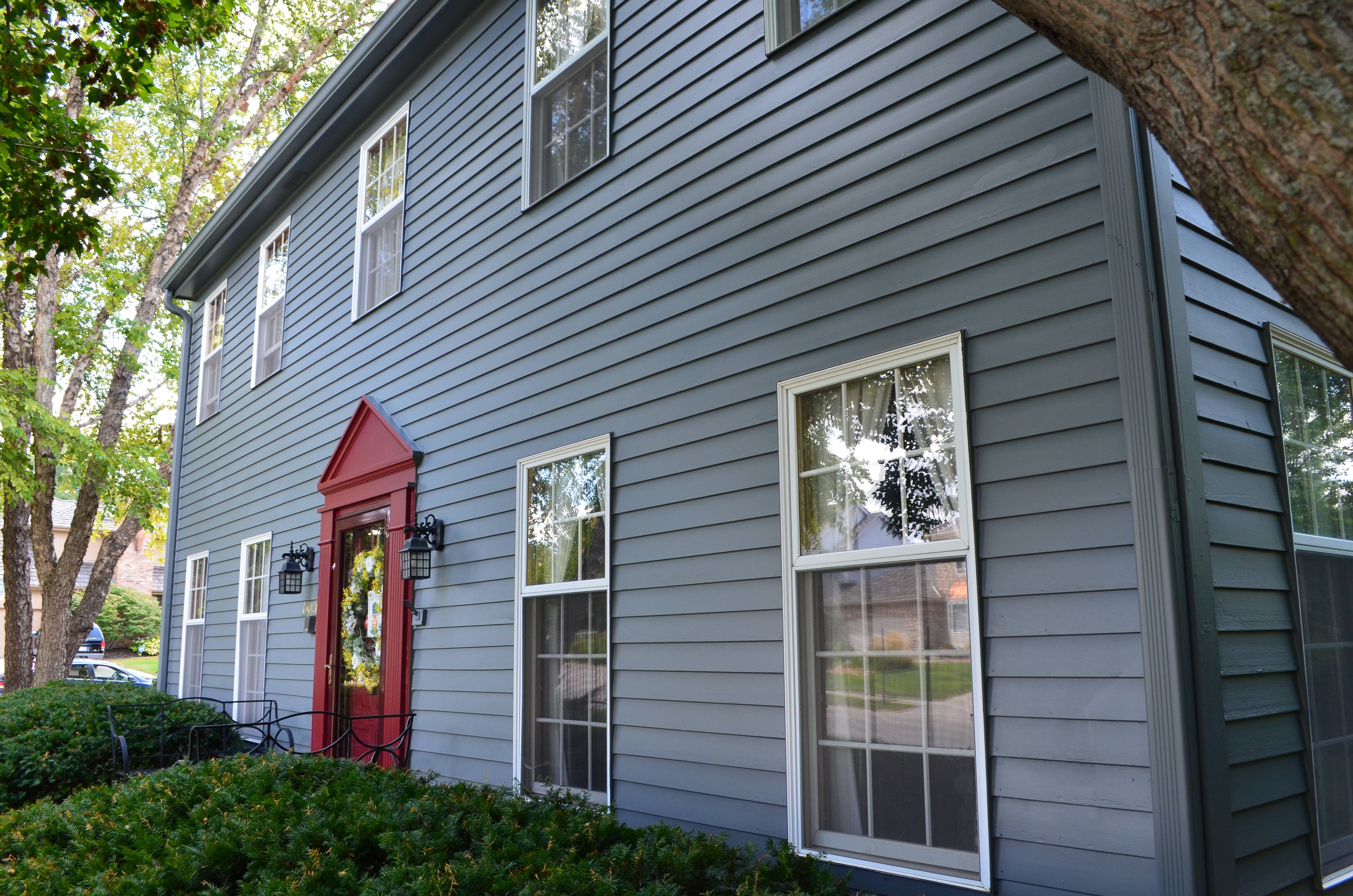 Exterior of a house painted blue with a red door and white window trim in Omaha, NE.