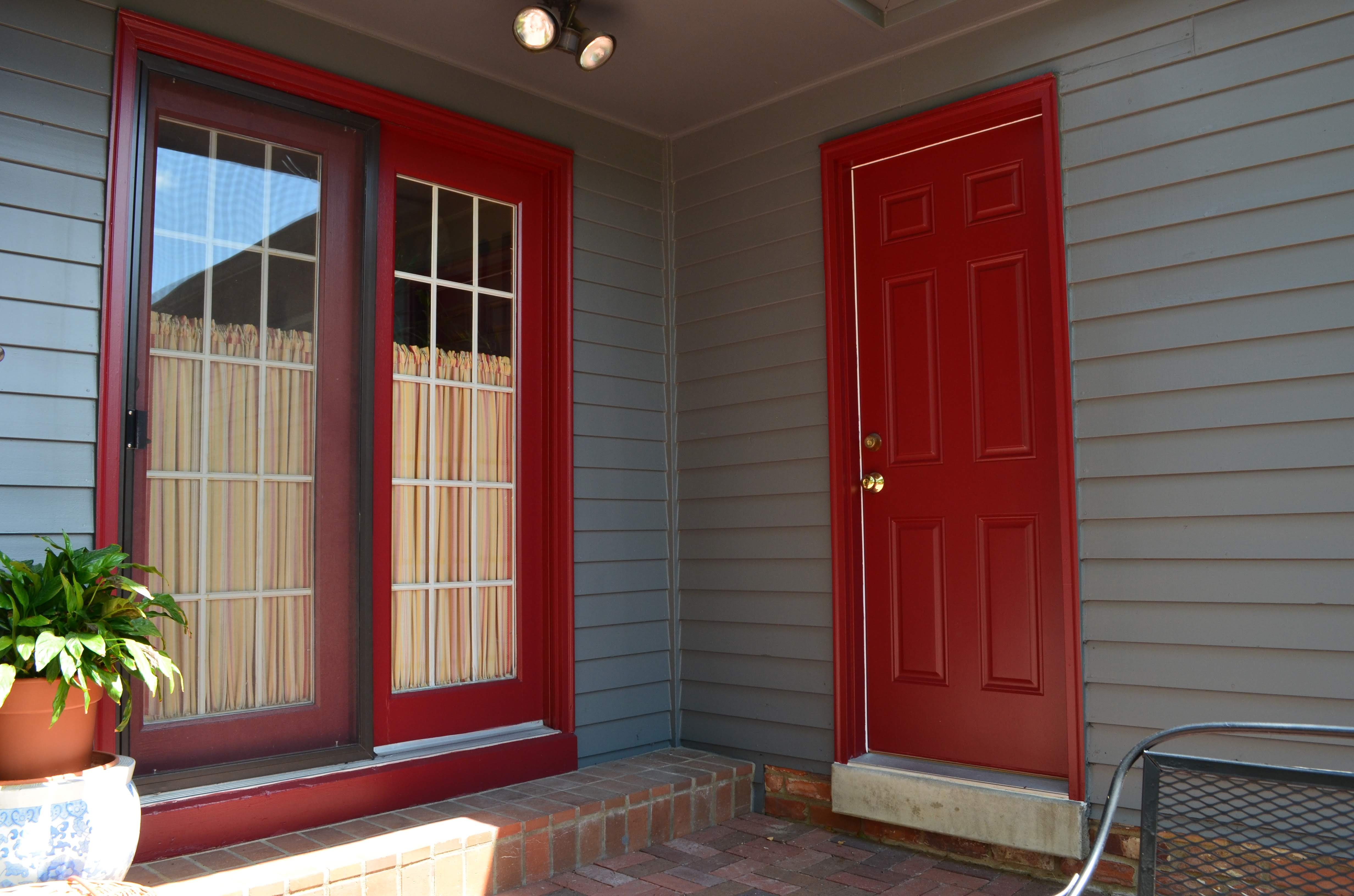 Backside of a home with deep blue painted siding and red window trim and door, in Omaha, NE.