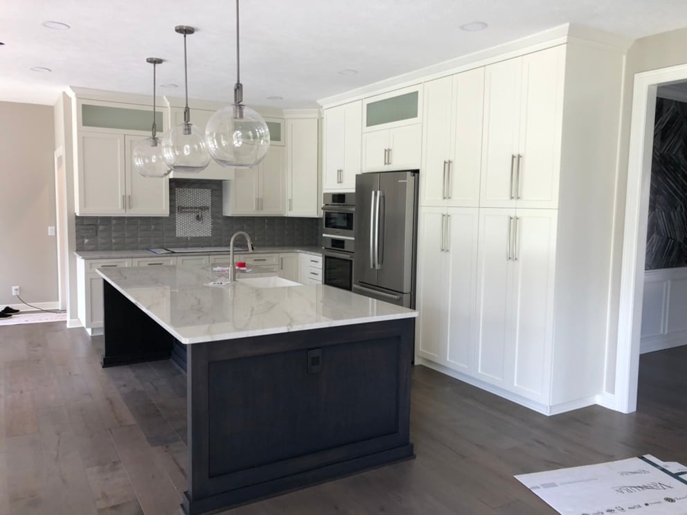 Kitchen with white painted cabinets and a black island with granite countertops and stainless steel appliances.