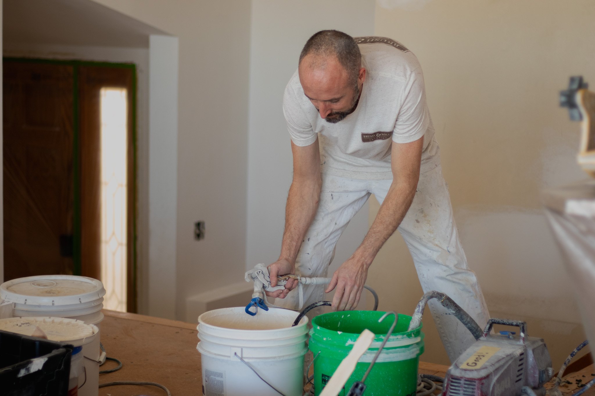 Painter getting paint out of a bucket to spray inside a home.