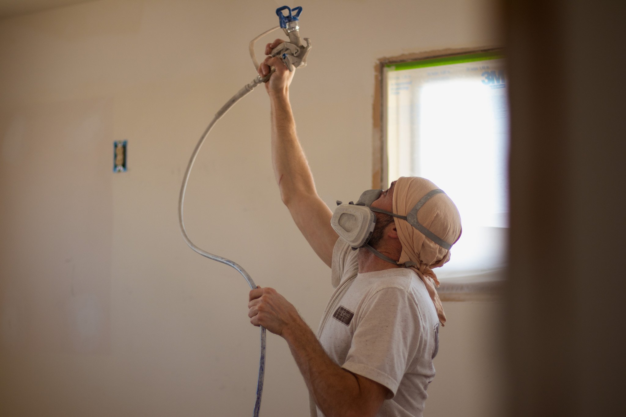 Brush & Roll Painting painter spraying ceiling white with a paint spray pump inside Omaha home.
