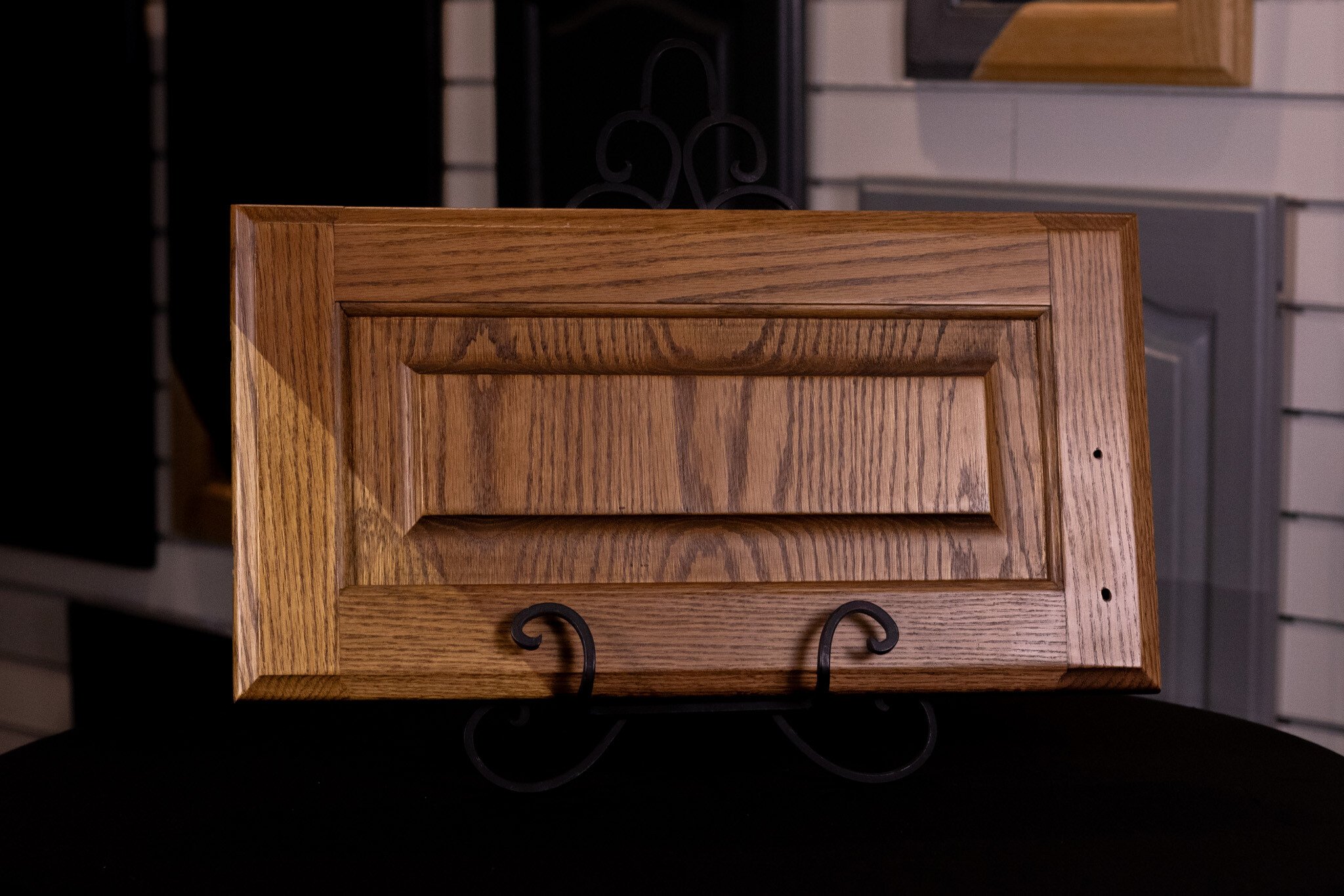 Oak cabinet door showing before and after of staining the door with a warm brown color.