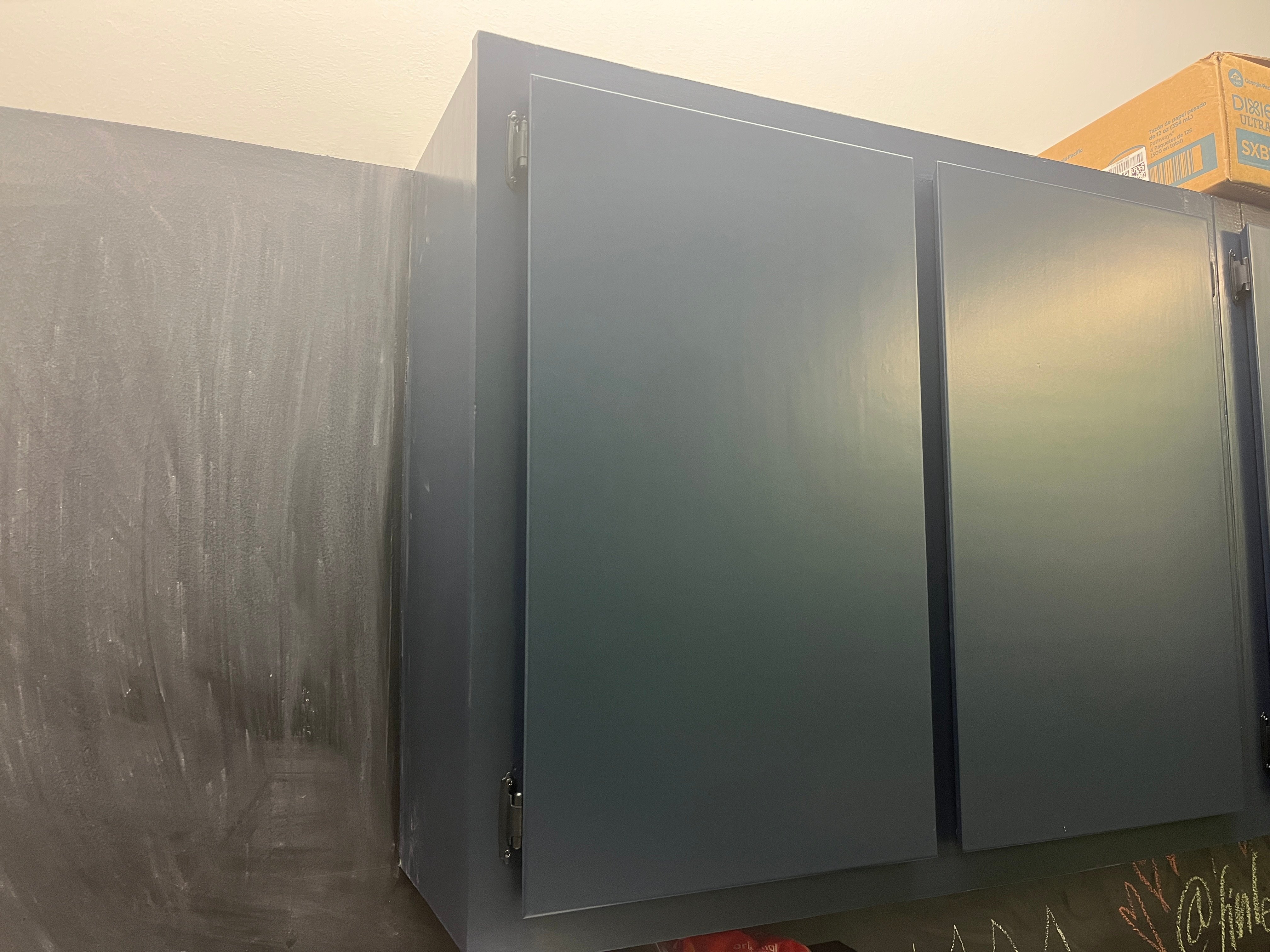 Navy blue painted cabinet in kitchen with chalk wall.