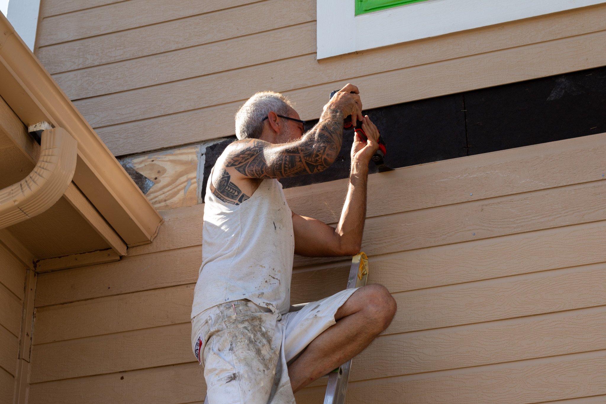 Painter replacing a siding piece before painting exterior in Omaha, NE.