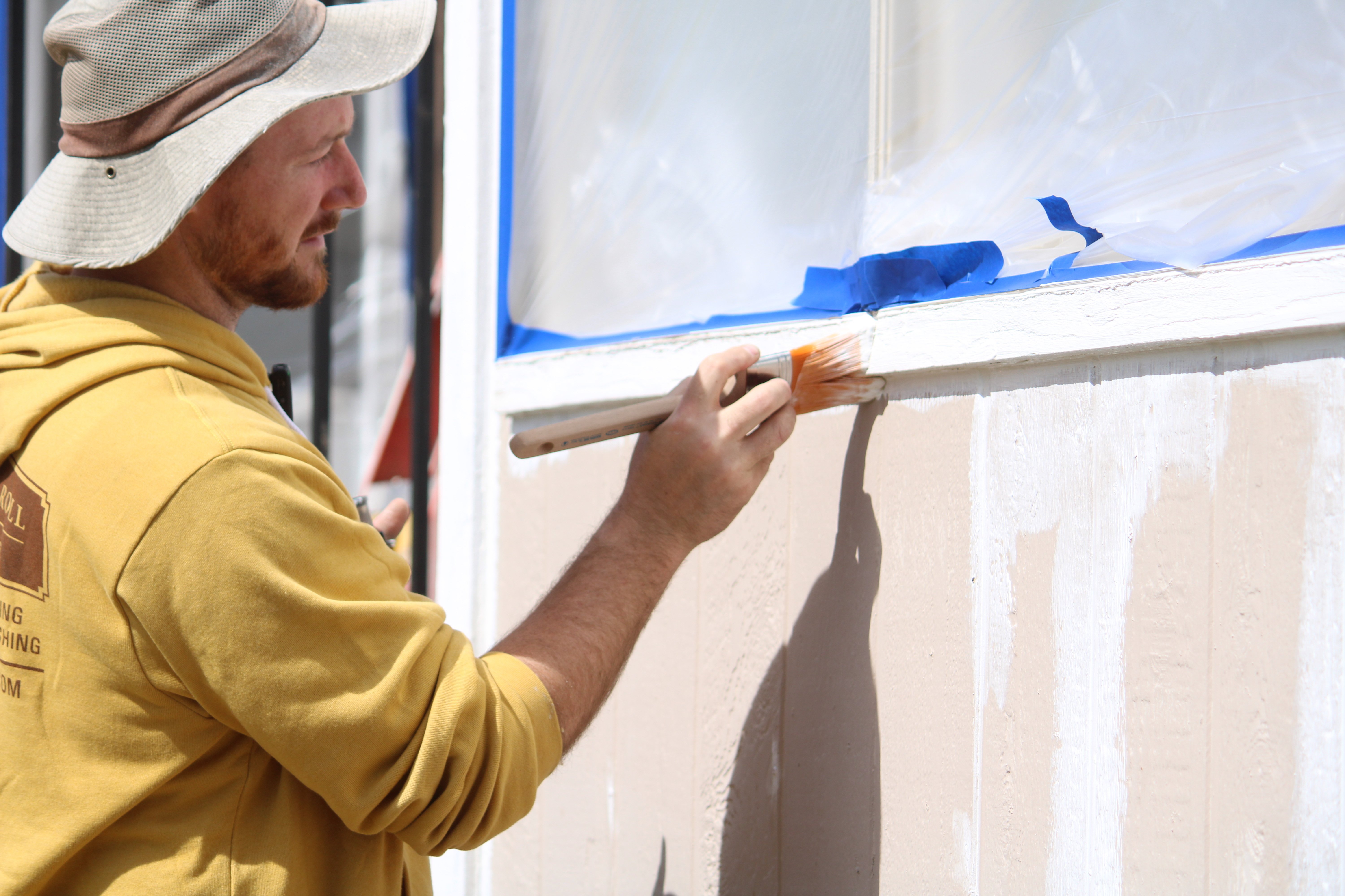 Brush & Roll Painting painter brushing white primer onto exterior house trim in Omaha, NE.