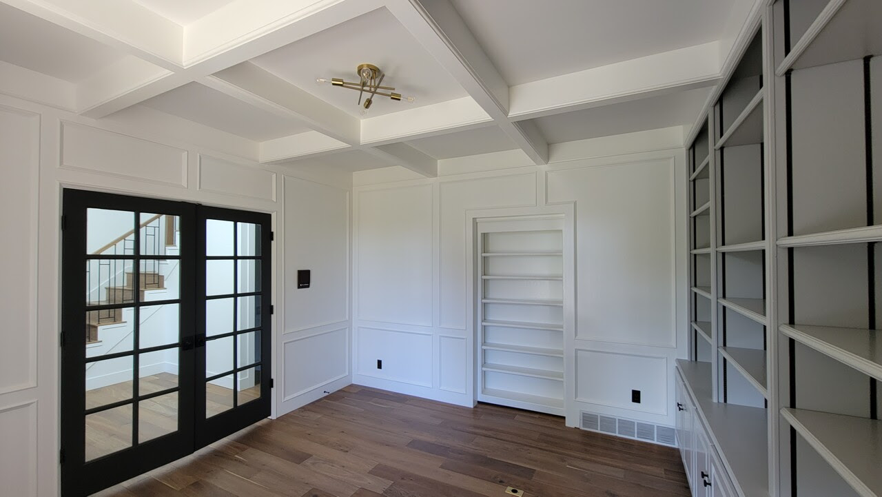 White walls and ceiling in home office space with wood floors and black window glass door.