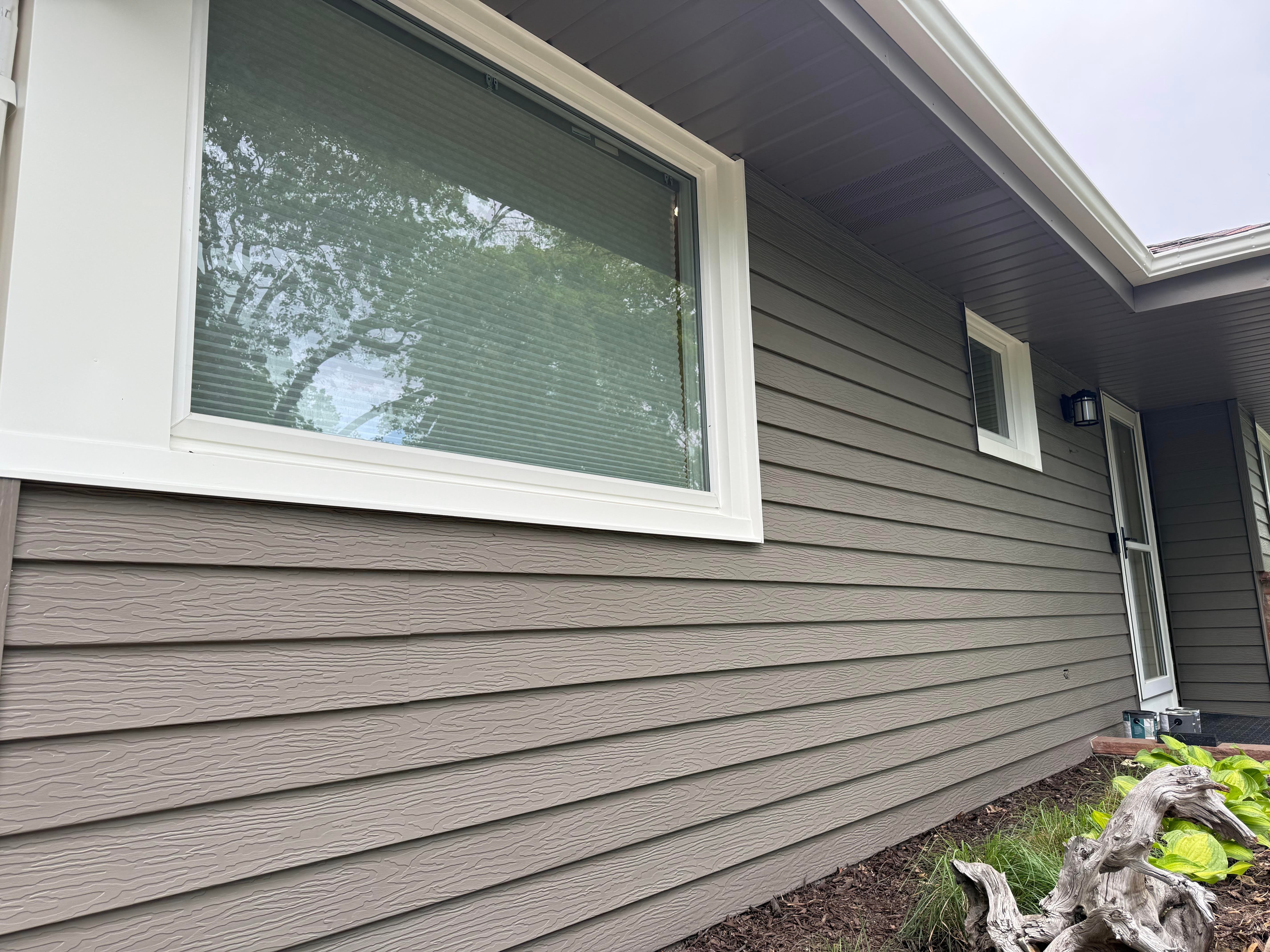 Exterior of a house with brown siding and white window trim.