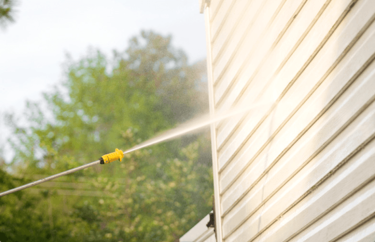 Power washer running water on home exterior.