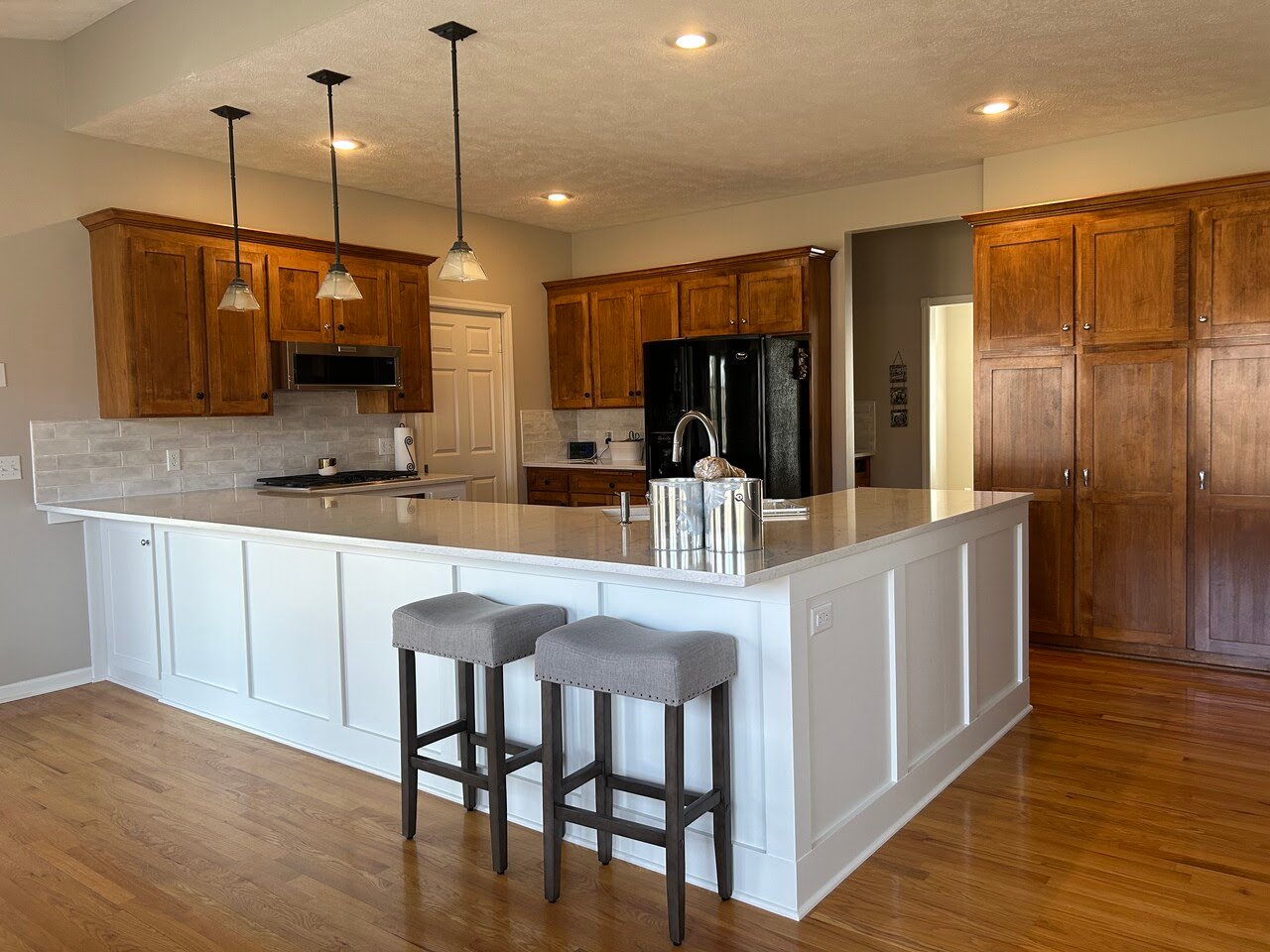 Kitchen with natural wood cabinets along the walls and an island painted white.
