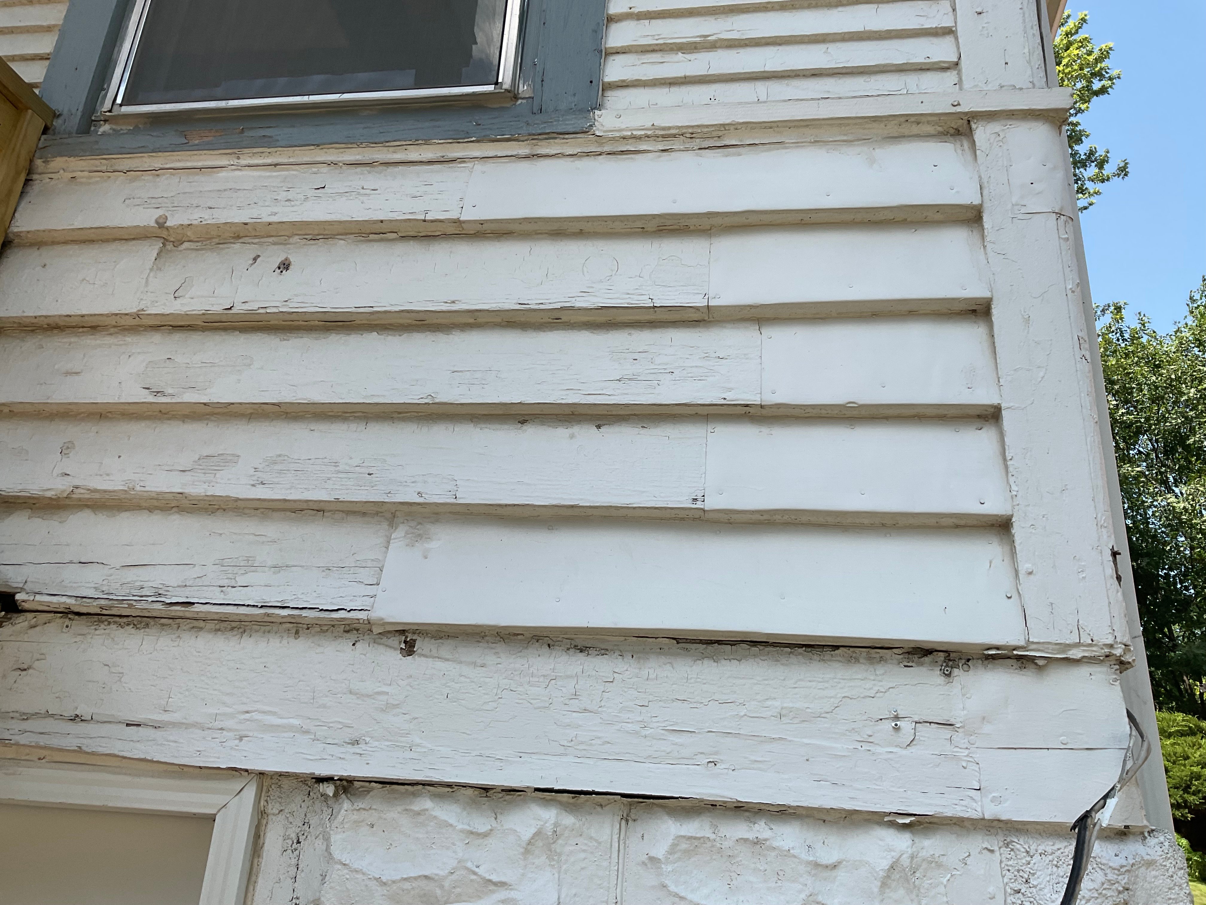 Peeling and damaged paint on the outside of a home painted white in Omaha, Nebraska.