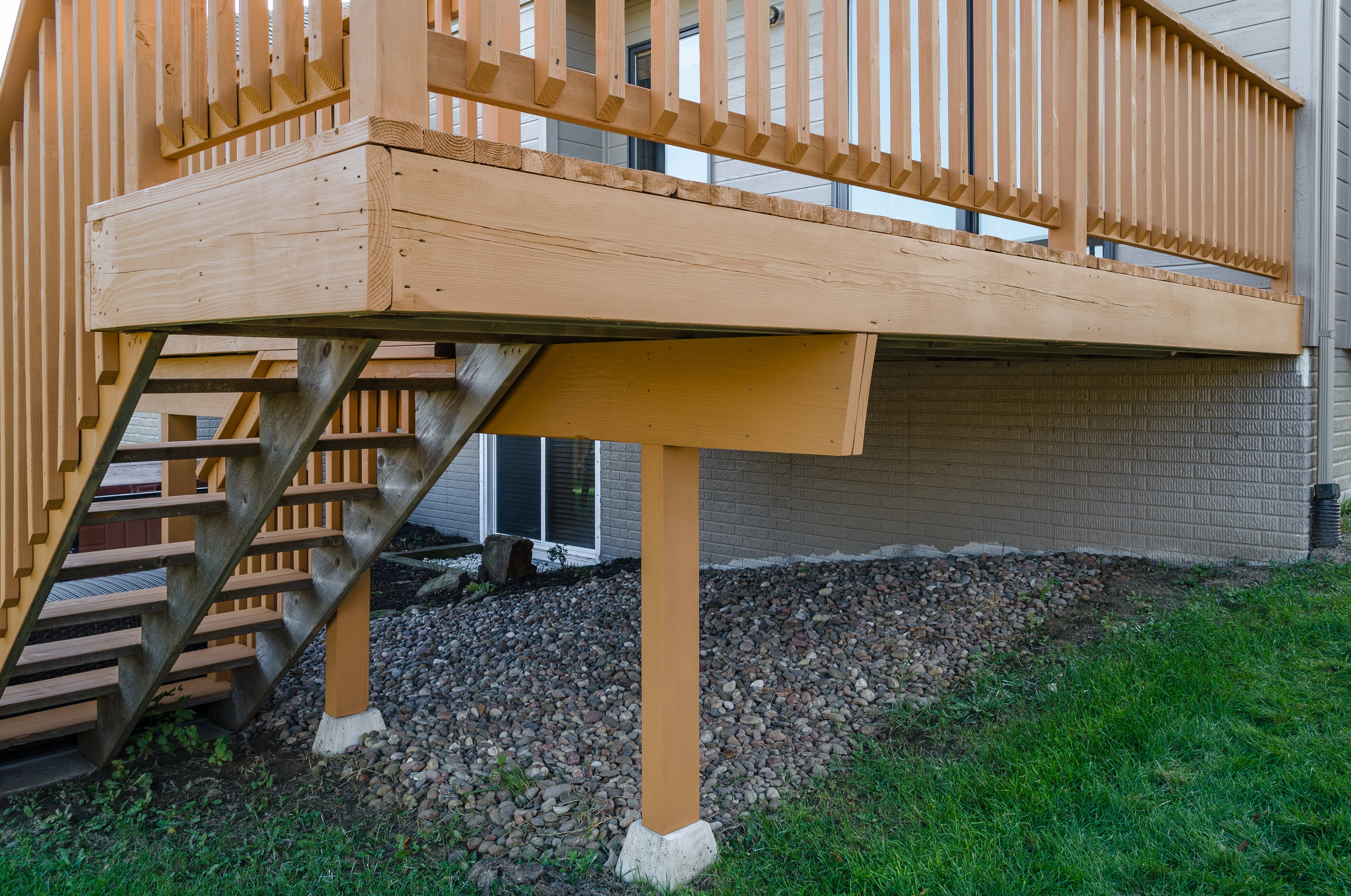Outside corner of a small deck with a light stain on the wood.