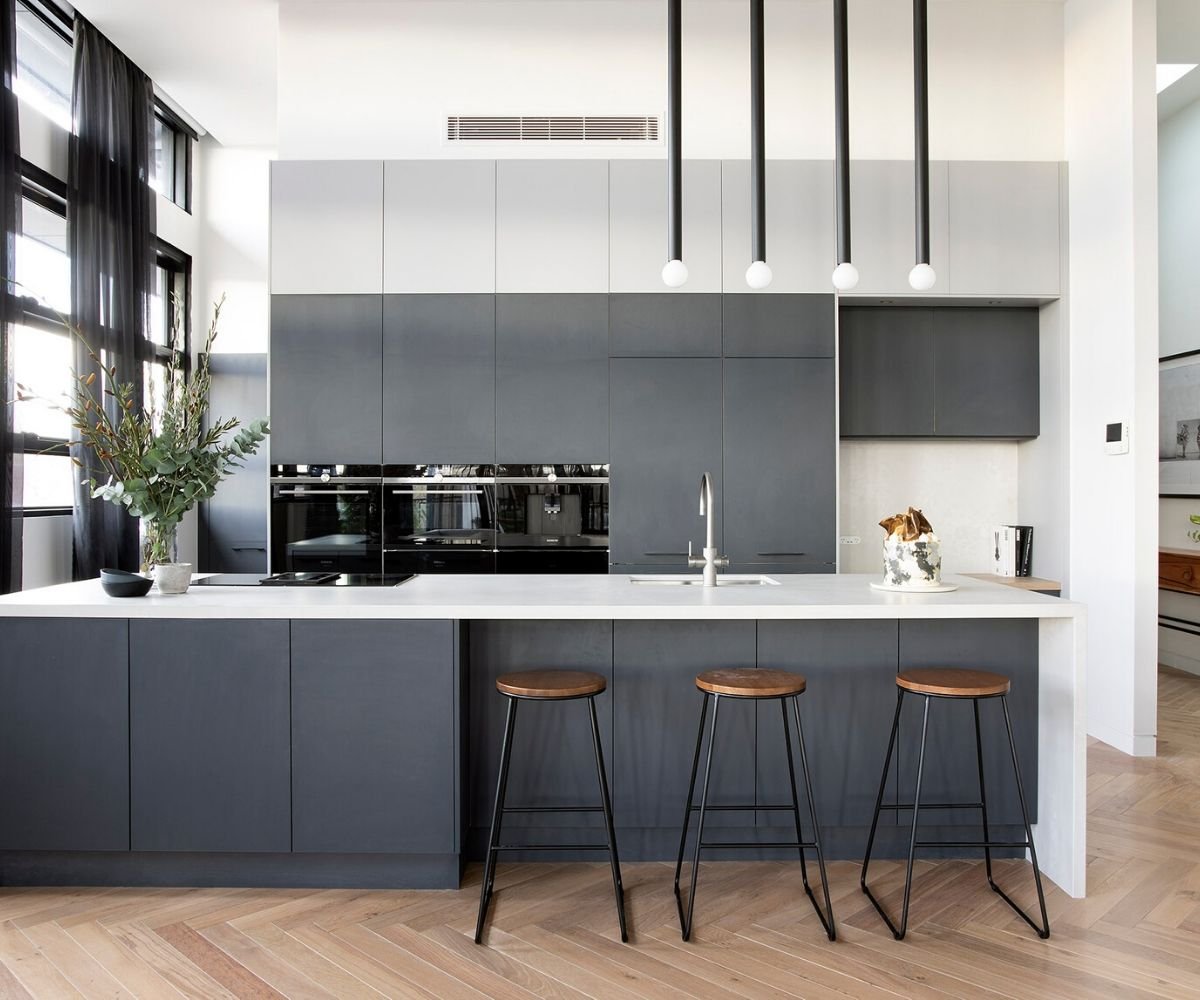 Modern kitchen with dark gray cabinets and white countertops.