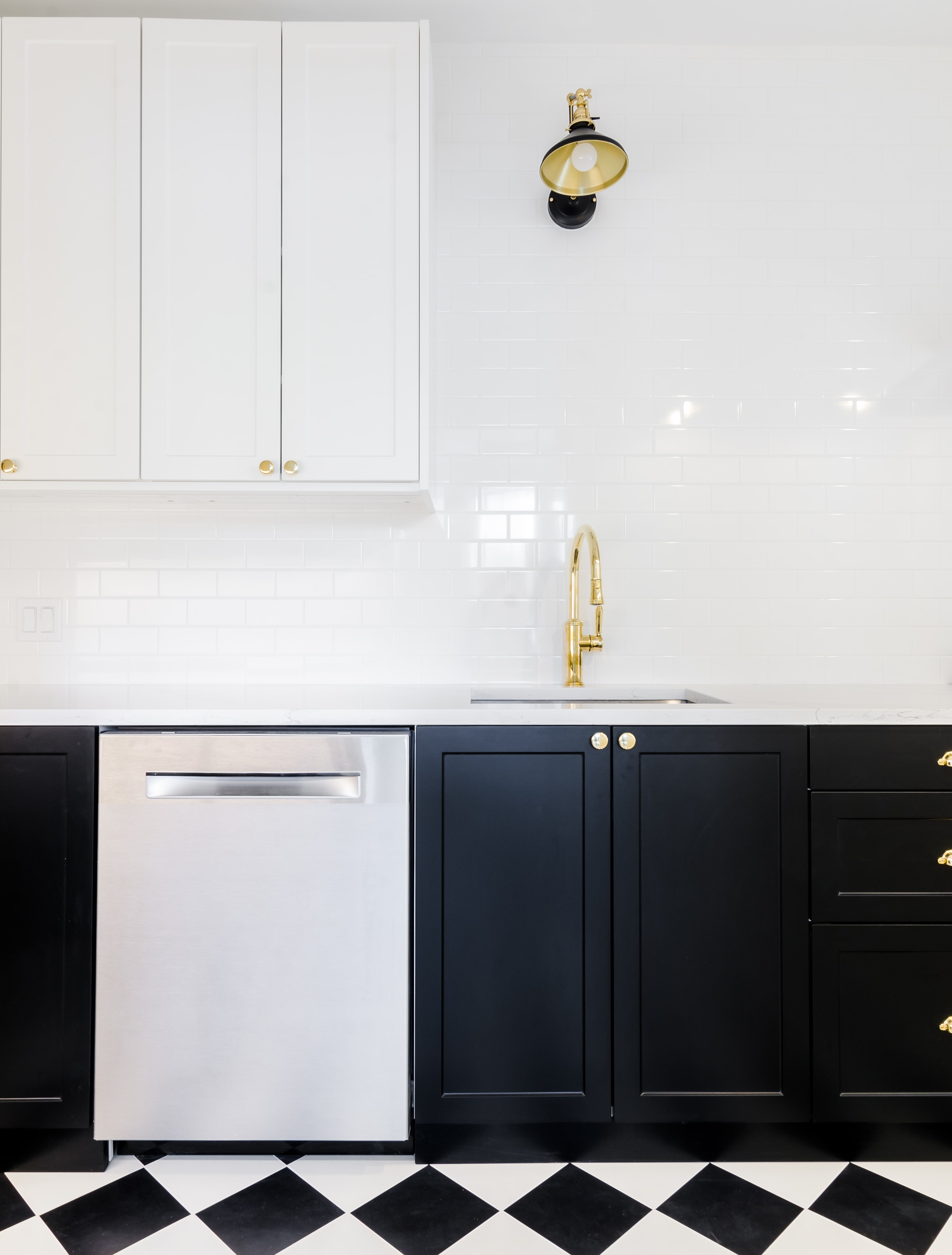 Kitchen with black lower cabinets and white upper cabinets with white backsplash.