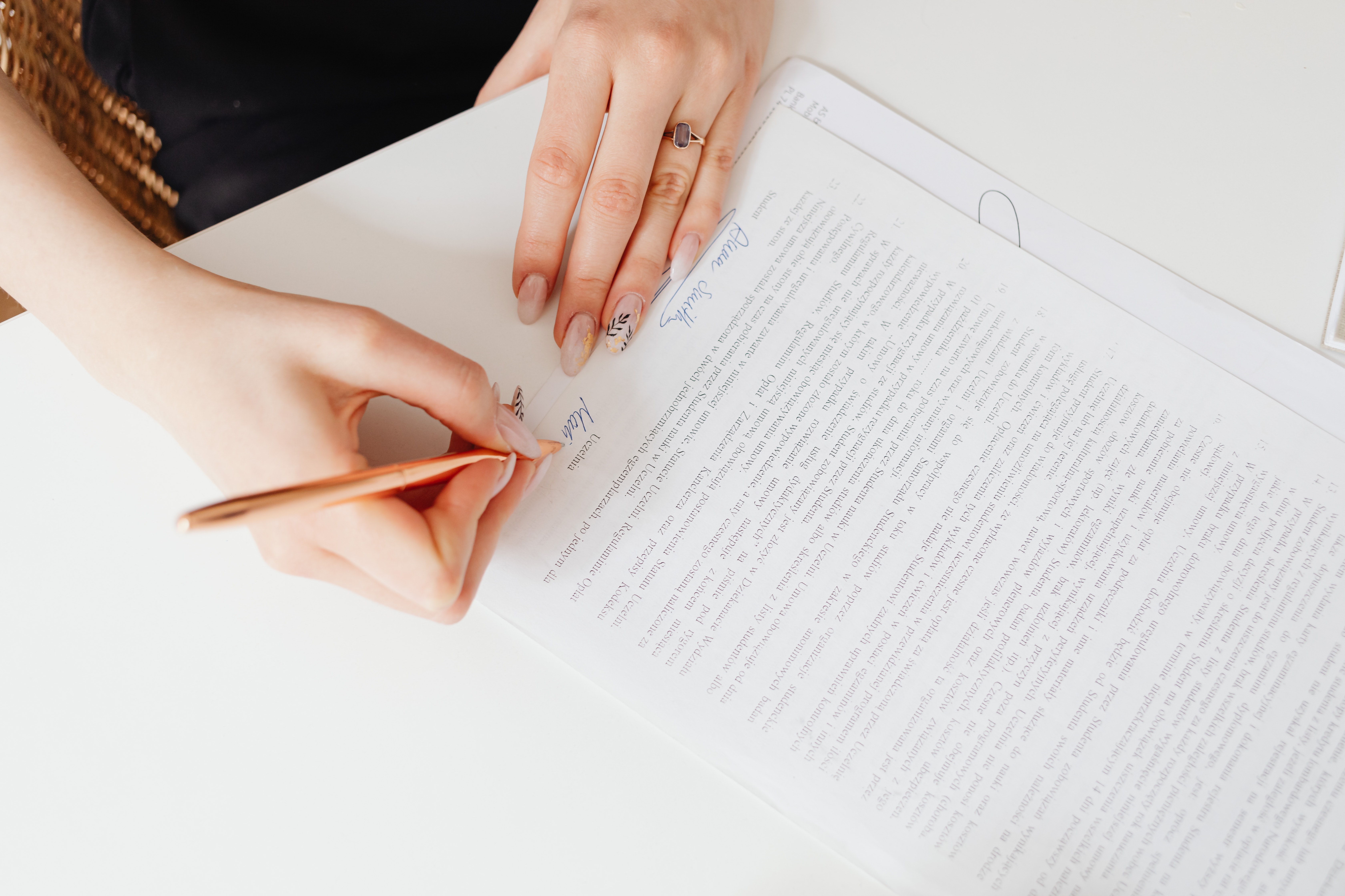 A person signing a paper agreement with a pencil
